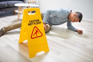 Injured person on the floor behind a wet floor sign. 