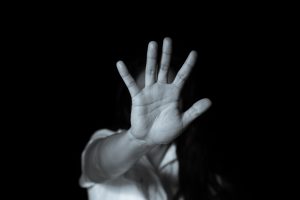 A black and white photo of a young person holding a hand out in front of their face.