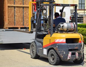 A forklift truck being used to unload heavy goods on a pallet.
