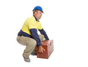 A construction worker lifting a tool box.