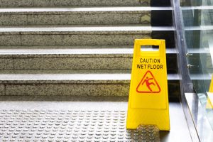 A wet floor sign at the bottom of a staircase. 